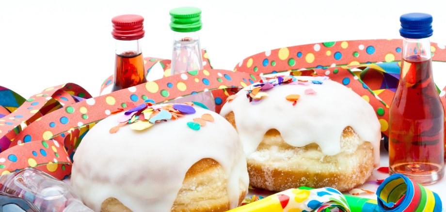 Berliner mit Zuckerguss, Likörflaschen und Tröten auf Konfetti
