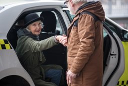 Lady sitting in auto while gentleman is holding her hand