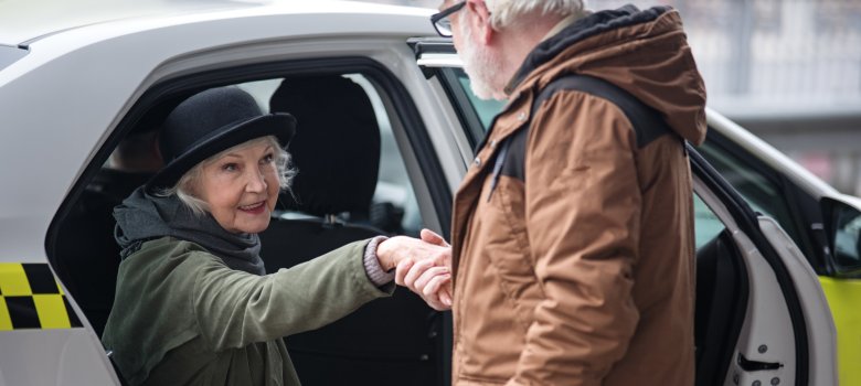 Lady sitting in auto while gentleman is holding her hand